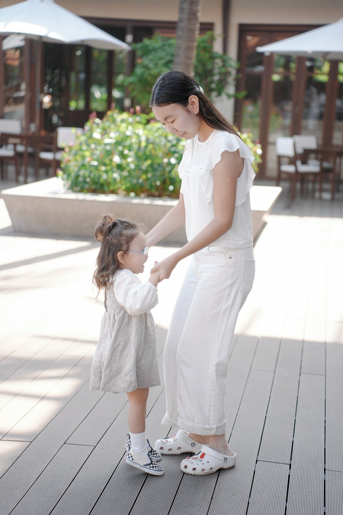 Woman holding hands with a young child outdoors